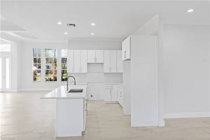 Kitchen with white cabinetry, recessed lighting, crown molding, an island with sink, and open floor plan
