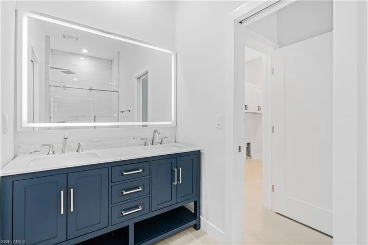Full bathroom with double vanity, a marble finish shower, and recessed lighting