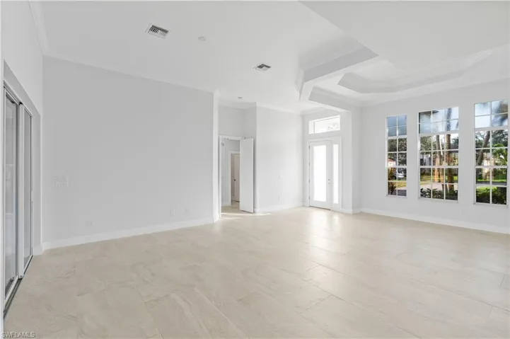 Unfurnished living room featuring crown molding and a raised ceiling