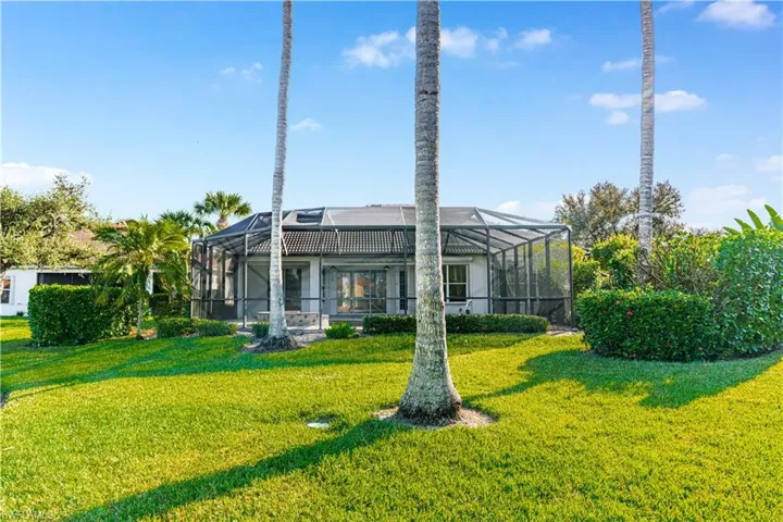 Rear view of property with glass enclosure, a sunroom, and a lawn