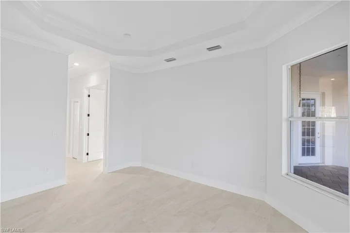 Empty room featuring a raised ceiling, recessed lighting, and crown molding