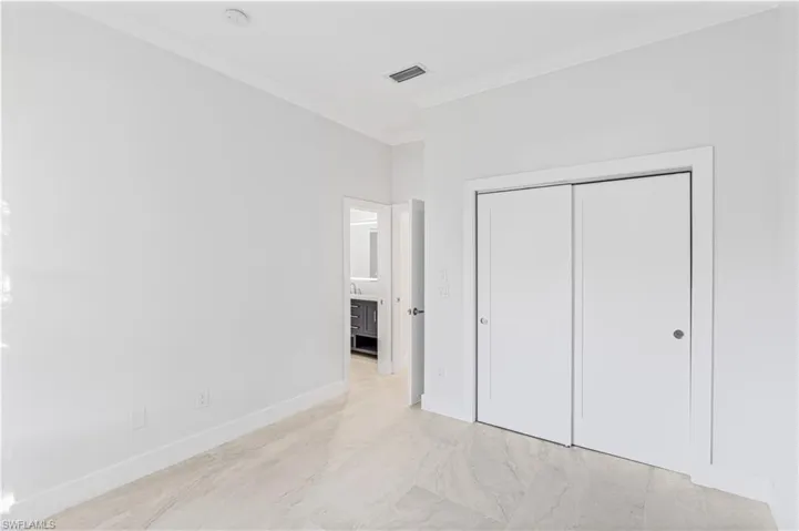 Unfurnished bedroom with ornamental molding, a closet, and light marble finish flooring