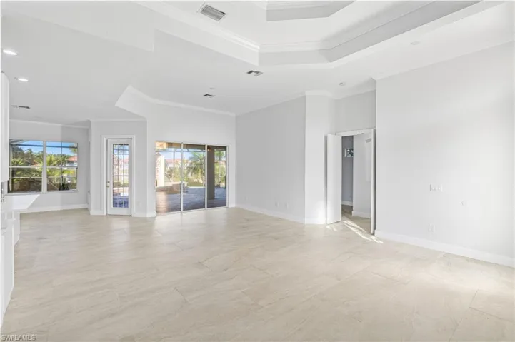 Empty room with a tray ceiling, ornamental molding, and recessed lighting