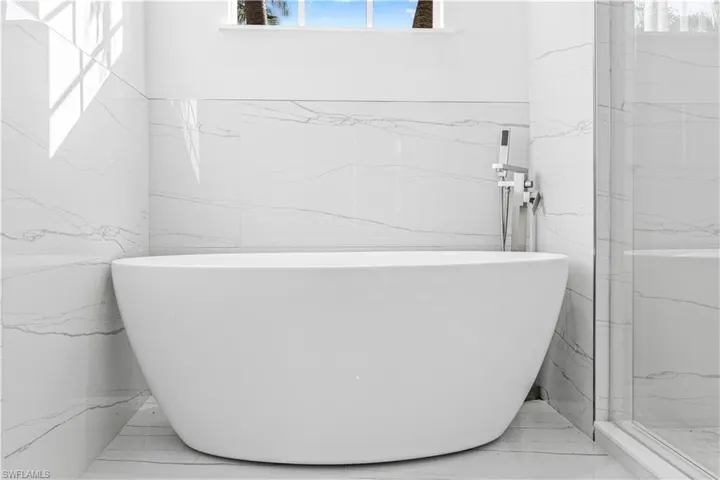 Full bathroom with a marble finish shower and a freestanding bath