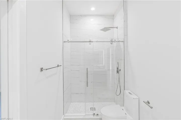 Full bath featuring a marble finish shower and toilet