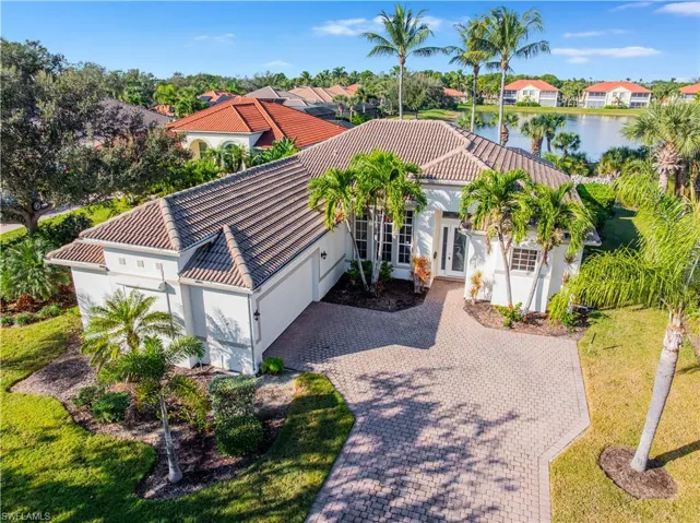 View of front facade featuring driveway, stucco siding, a tiled roof, and a water view