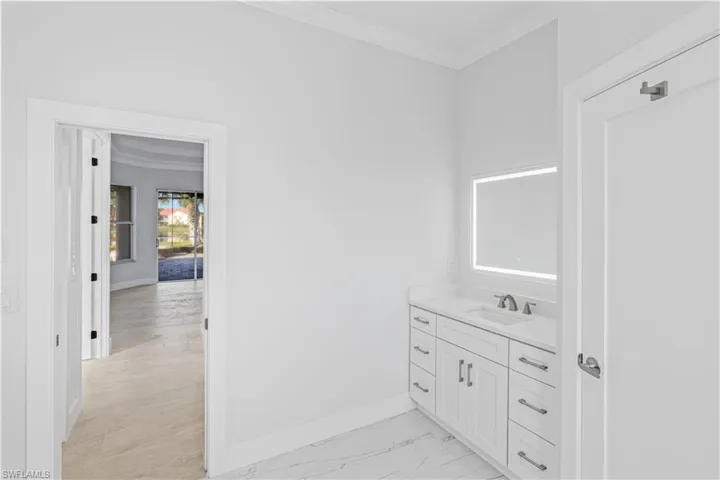 Bathroom with crown molding, vanity, and light marble finish flooring