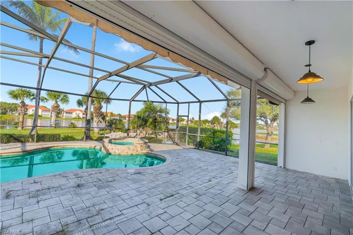View of pool with a patio area, glass enclosure, a sunroom, and a pool with connected hot tub