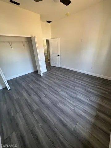 Unfurnished bedroom with a closet, a ceiling fan, and dark wood-style floors