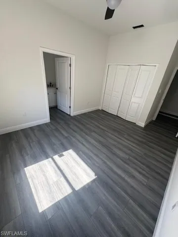 Unfurnished bedroom with wood finished floors, a closet, a ceiling fan, and connected bathroom
