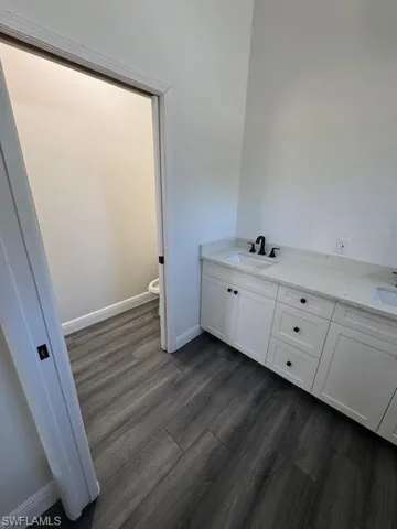 Full bath featuring double vanity and dark wood finished floors