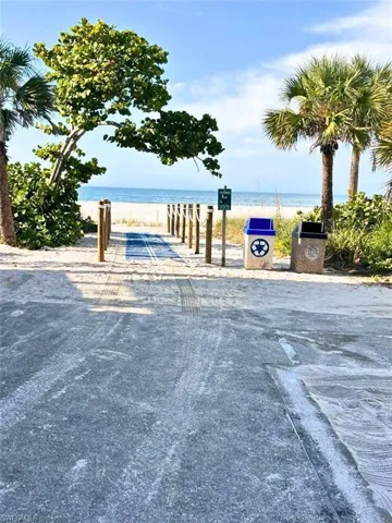 View of asphalt road featuring a boat ramp and view of water and beach VIRTUALLY EDITED