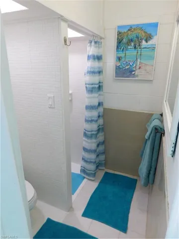 Bathroom featuring a shower stall and tile walls