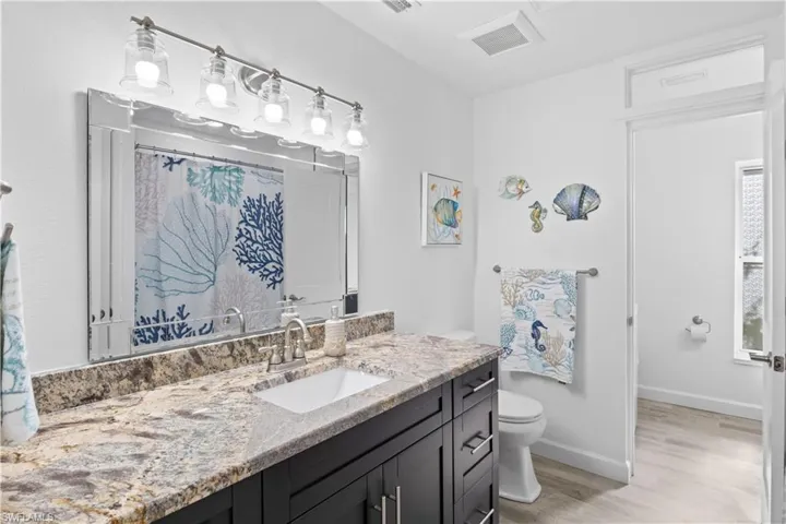 Bath and shower combo with accented tile, custom vanity with granite counter top.
