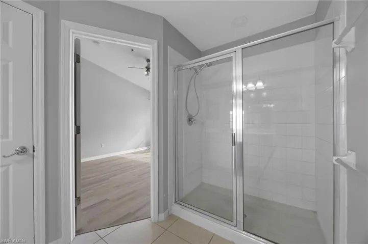 Full bath with a shower stall, light tile patterned floors, and ceiling fan