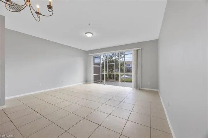 Empty room with a chandelier and light tile patterned floors