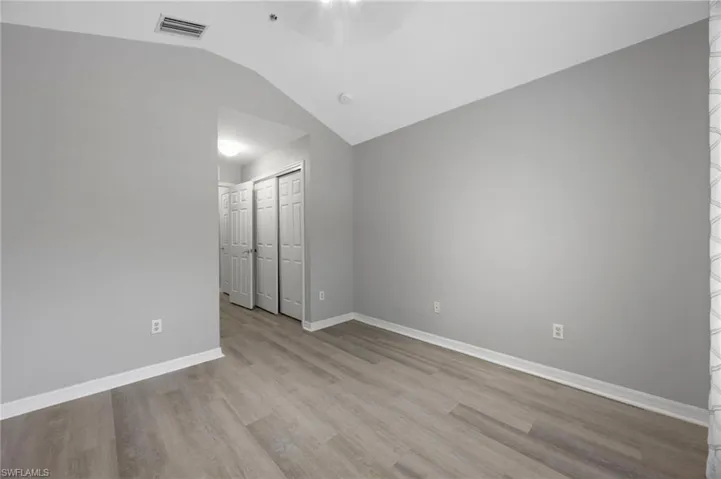 Spare room with vaulted ceiling and light wood finished floors