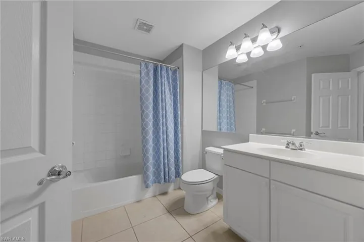 Bathroom with vanity, shower / tub combo with curtain, and light tile patterned floors