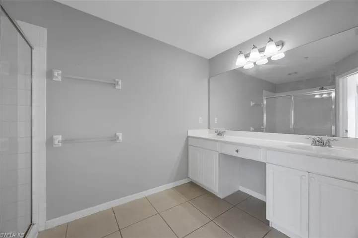 Full bath with a stall shower, double vanity, and light tile patterned floors