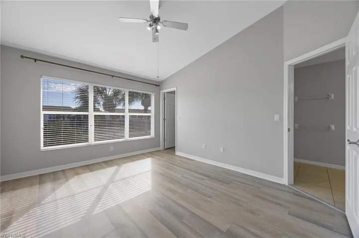 Empty room with light wood-style floors, vaulted ceiling, and a ceiling fan