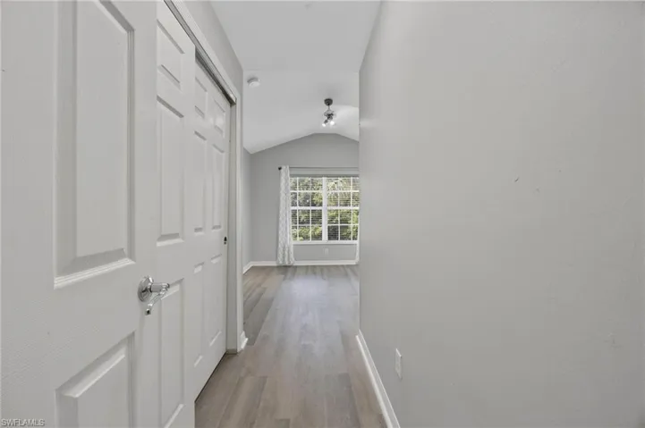 Corridor with lofted ceiling and light wood-style floors