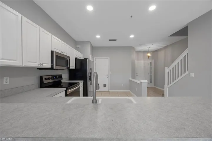 Kitchen featuring white cabinets, stainless steel appliances, light countertops, recessed lighting, and light tile patterned floors