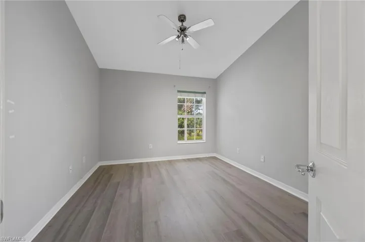 Empty room with light wood finished floors, a ceiling fan, and lofted ceiling
