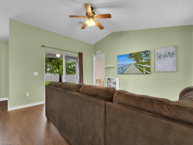 Living room featuring lofted ceiling, ceiling fan, and dark hardwood / wood-style flooring