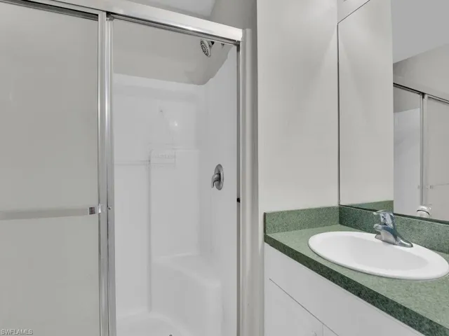 Bathroom featuring a shower with shower door and vanity