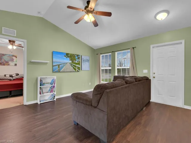Living room featuring dark hardwood / wood-style flooring, ceiling fan, and lofted ceiling