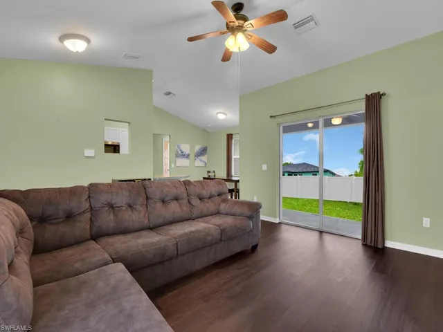 Living room with dark wood-type flooring, lofted ceiling, and ceiling fan