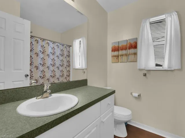 Bathroom featuring vanity with extensive cabinet space, toilet, and wood-type flooring