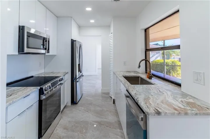 Kitchen featuring stainless steel appliances, modern cabinets, light stone counters, white cabinetry, and recessed lighting