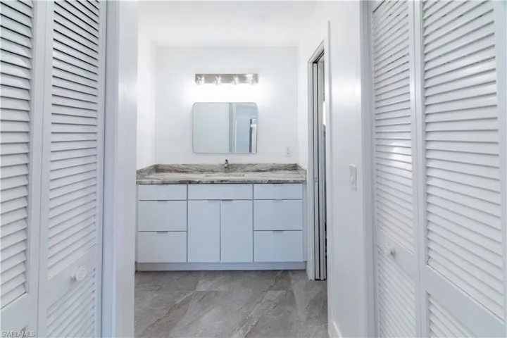 Bathroom featuring a closet, vanity, and light marble finish floors