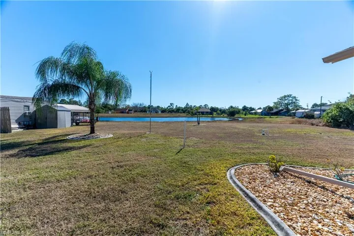 View of green lawn with a water view, a shed, and a residential view