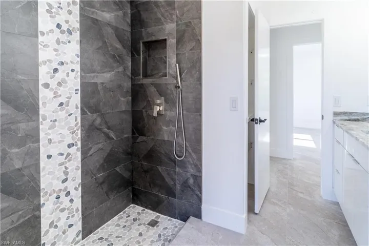 Bathroom featuring tiled shower and vanity