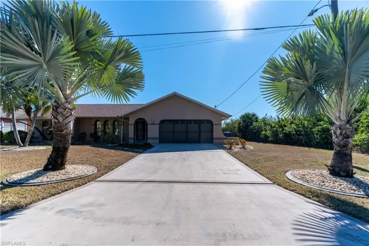 View of front of property featuring stucco siding, concrete driveway, a garage, and a front yard