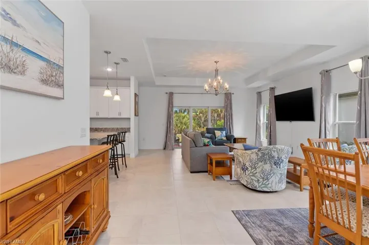 Living area with a raised ceiling, hanging lights, and light tile patterned flooring