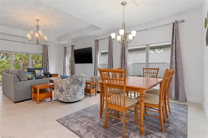 Dining area featuring hanging lights, a tray ceiling, and light tile patterned flooring