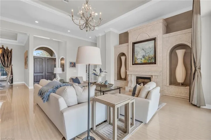 Living room featuring a premium fireplace, light hardwood / wood-style floors, ornamental molding, and an inviting chandelier