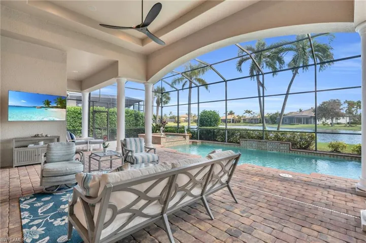 View of patio / terrace with glass enclosure, a pool with hot tub, ceiling fan, pool water feature, and a water view