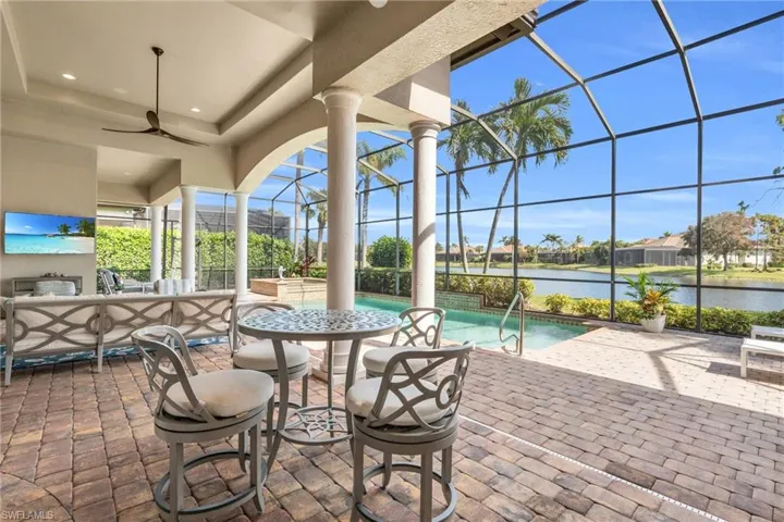 View of patio with ceiling fan, a water view, and glass enclosure