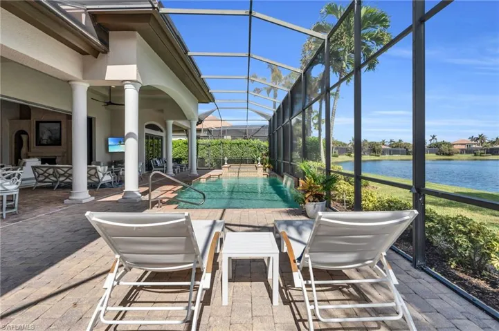 View of swimming pool featuring a patio, a water view, glass enclosure, and ceiling fan