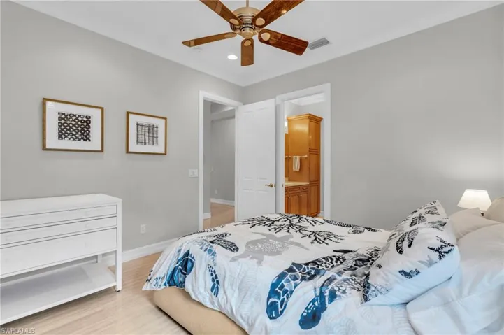 Bedroom with light hardwood / wood-style flooring, ceiling fan, and ensuite bath