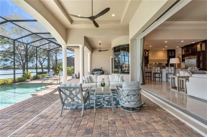 View of patio featuring a bar, outdoor lounge area, a lanai, a water view, and ceiling fan