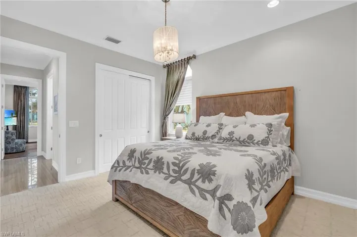 Bedroom with a chandelier, crown molding, light wood-type flooring, and a closet