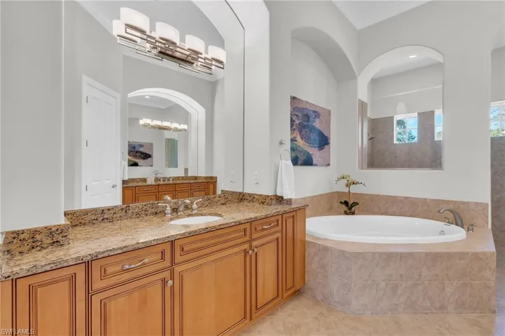Bathroom featuring vanity, ornamental molding, tile patterned flooring, and tiled bath