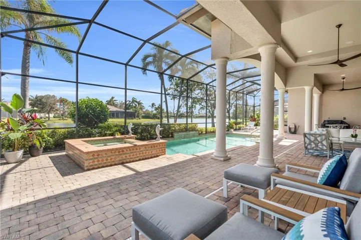 View of patio featuring glass enclosure, ceiling fan, and a pool with hot tub