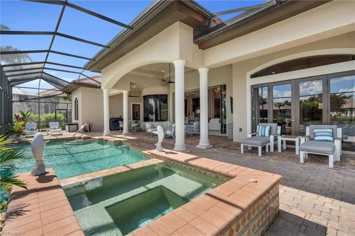 View of swimming pool featuring a patio area, ceiling fan, an in ground hot tub, and glass enclosure