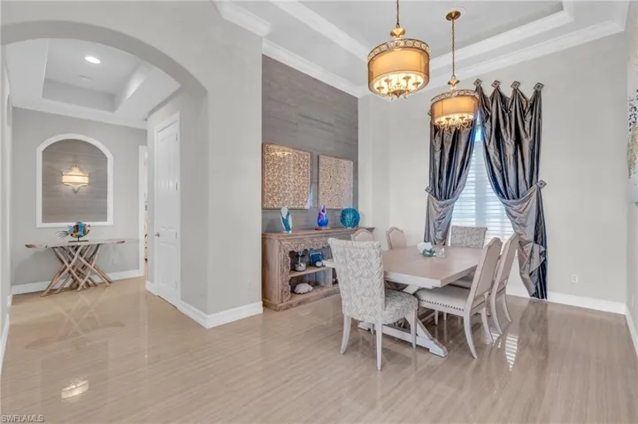 Dining area featuring crown molding, a raised ceiling, and an inviting chandelier